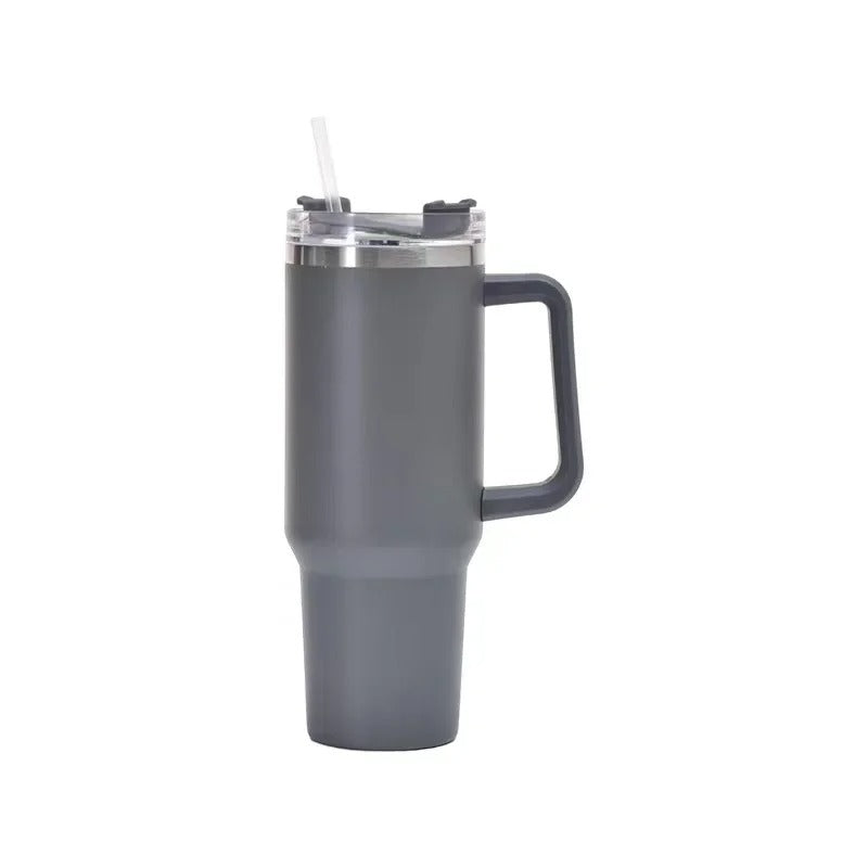 Un accessoire au ton gris anthracite affichant une forme élancée et une texture lisse. Le couvercle transparent laisse apparaître le mécanisme d’ouverture et une paille rigide. L’anse angulaire, fixée sur le côté, offre une prise en main équilibrée. L’arr